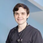 Dr. Cravens, male veterinarian smiling and wearing dark scrubs and a stethoscope