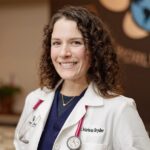Female Veterinarian with short brown curly hair wearing a white lab coat